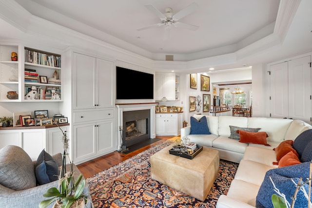 3121 Marshgate Dr, Seabrook Island, SC 29455 - living area featuring wood finished floors, a fireplace with flush hearth, a ceiling fan, a chandelier, and a tray ceiling