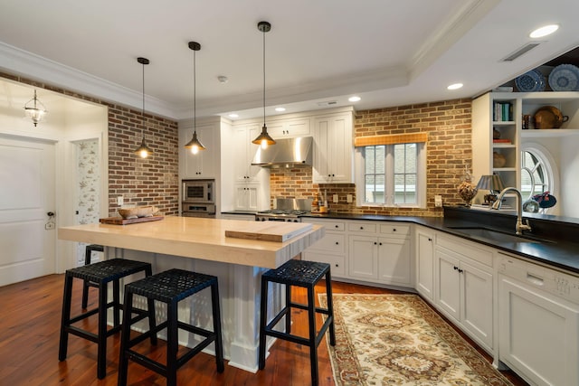 3121 Marshgate Dr, Seabrook Island, SC 29455 - kitchen featuring ventilation hood, ornamental molding, butcher block countertops, stainless steel microwave, and wood finished floors