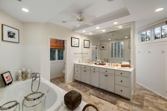 3121 Marshgate Dr, Seabrook Island, SC 29455 - bathroom with ceiling fan, double vanity, a jetted tub, a wainscoted wall, and brick patterned flooring