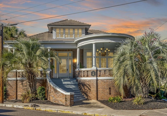 view of front of property featuring covered porch, a tile roof, and stucco siding