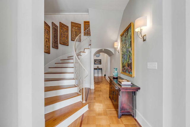 staircase with arched walkways and baseboards