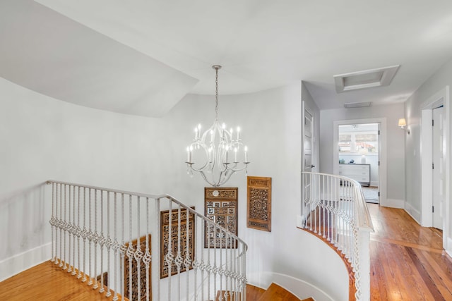 hall with attic access, baseboards, wood finished floors, and an upstairs landing