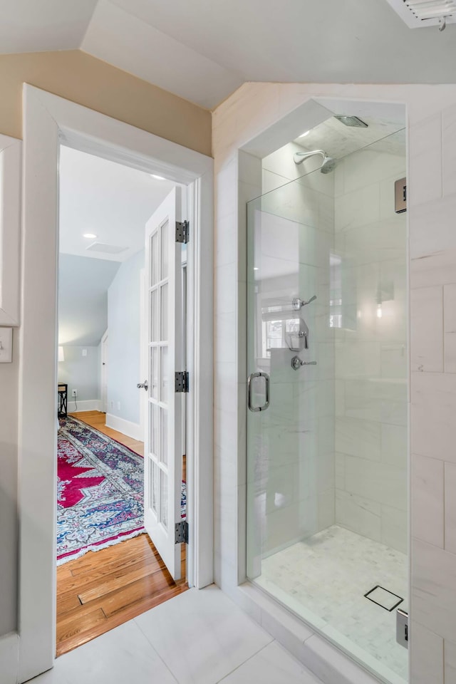 bathroom featuring a stall shower, lofted ceiling, and wood finished floors