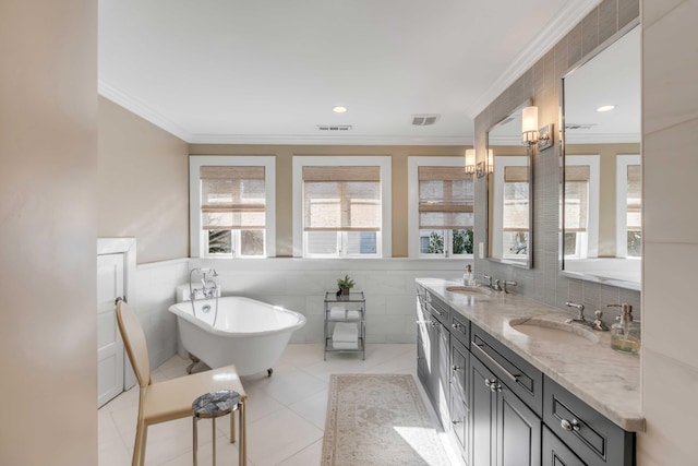 bathroom with ornamental molding, a freestanding tub, visible vents, and a sink