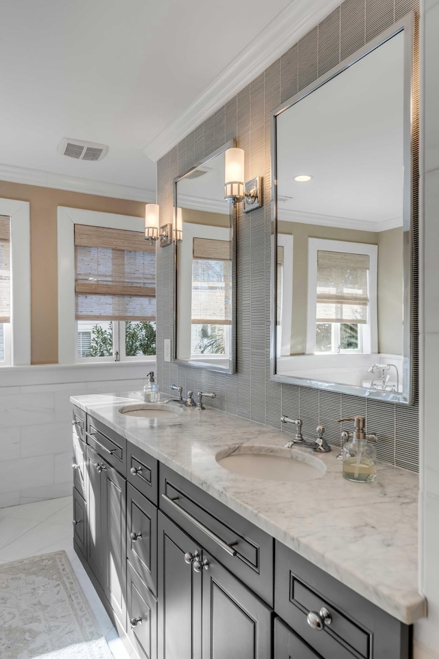 bathroom with ornamental molding, visible vents, a sink, and tile walls