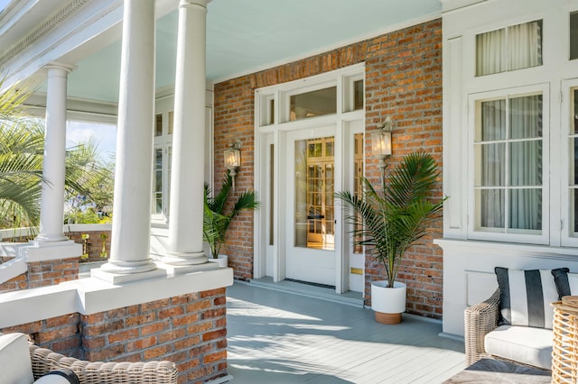 doorway to property featuring covered porch and brick siding