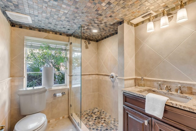 full bathroom with toilet, a shower stall, tile walls, and vanity