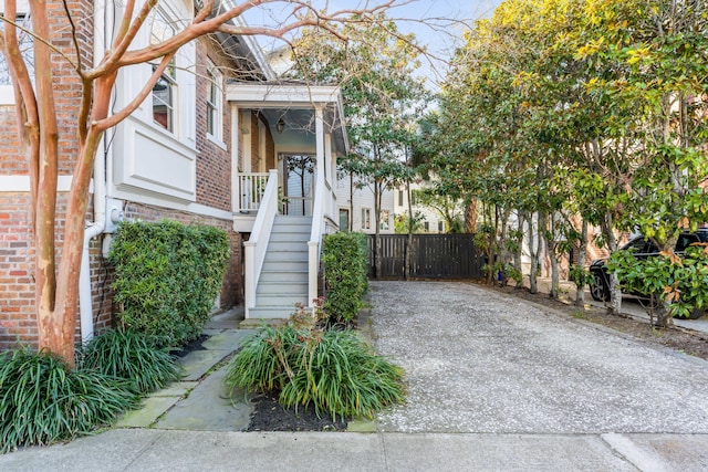 view of exterior entry featuring brick siding and fence