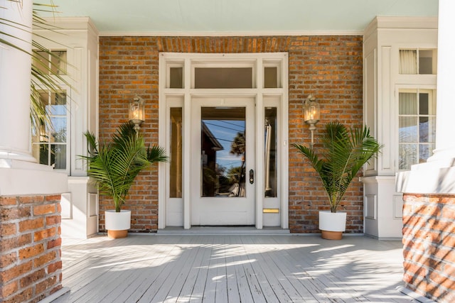 view of exterior entry with brick siding and a porch