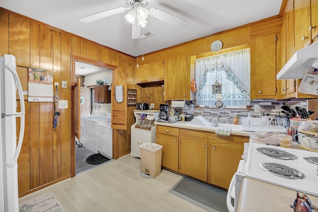 kitchen featuring visible vents, washer and dryer, white appliances, wood walls, and light countertops