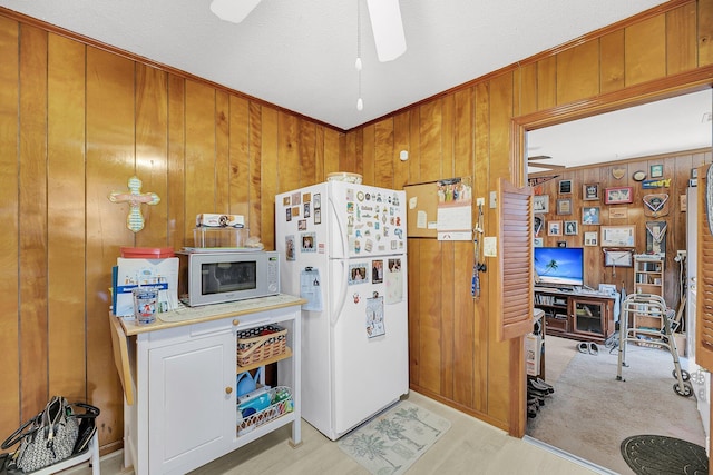 kitchen with brown cabinets, white appliances, wood walls, light countertops, and ceiling fan