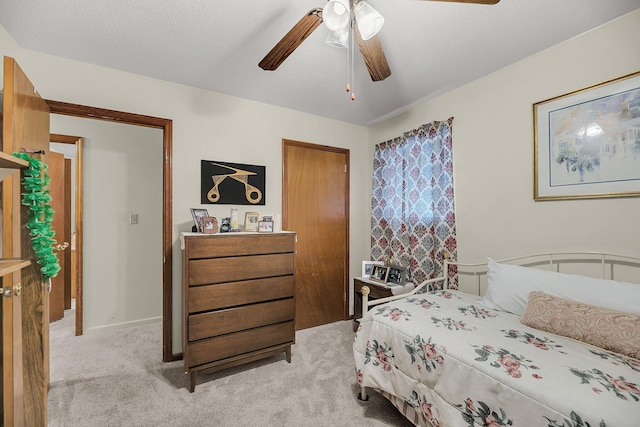 bedroom featuring baseboards, light colored carpet, a ceiling fan, and a textured ceiling