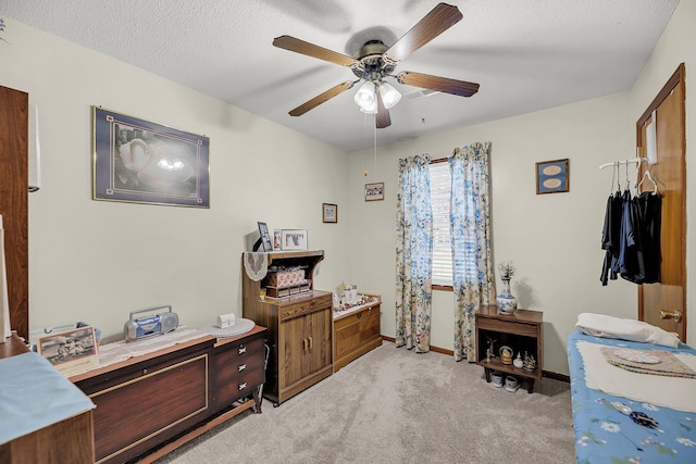 office area with light colored carpet, a textured ceiling, baseboards, and ceiling fan