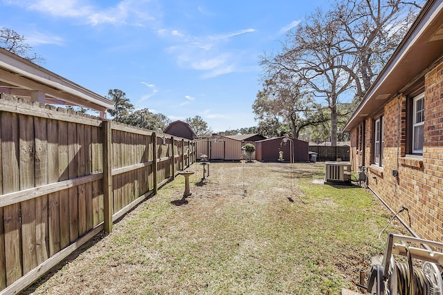 view of yard with an outdoor structure, central air condition unit, a fenced backyard, and a shed