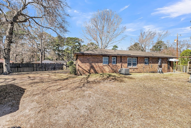 back of house featuring brick siding, central air condition unit, and fence