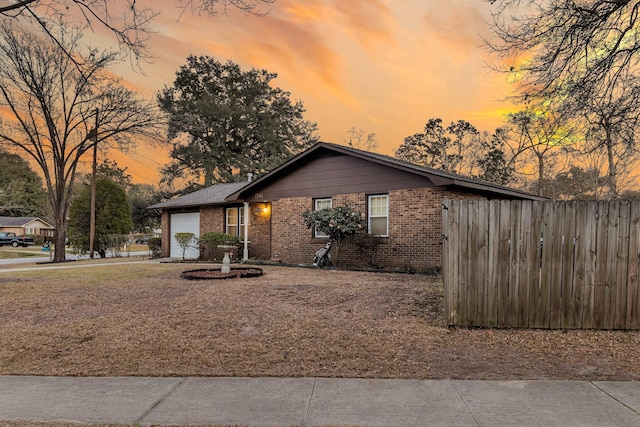 view of front of home featuring a garage, brick siding, and fence