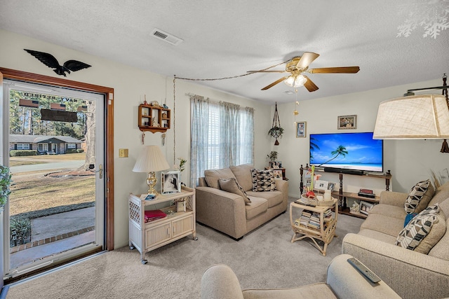 carpeted living room featuring visible vents, a textured ceiling, and ceiling fan