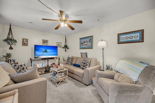 living room featuring visible vents, light carpet, a textured ceiling, and ceiling fan