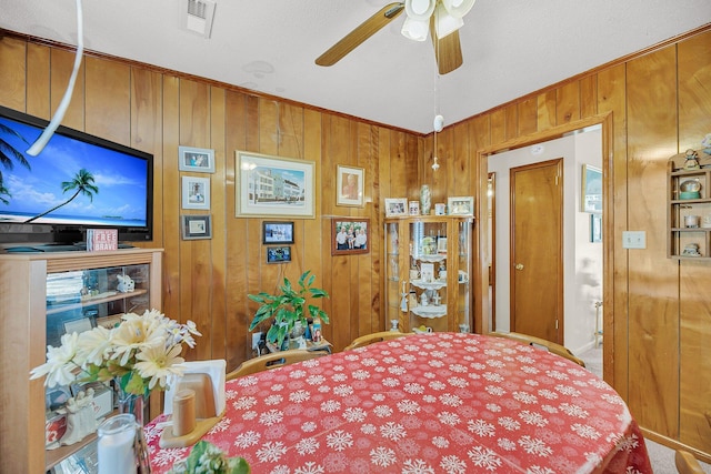 bedroom featuring wooden walls, visible vents, and ceiling fan