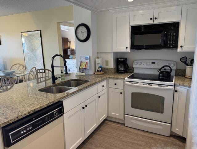 kitchen featuring light stone countertops, white appliances, sink, hardwood / wood-style floors, and white cabinetry