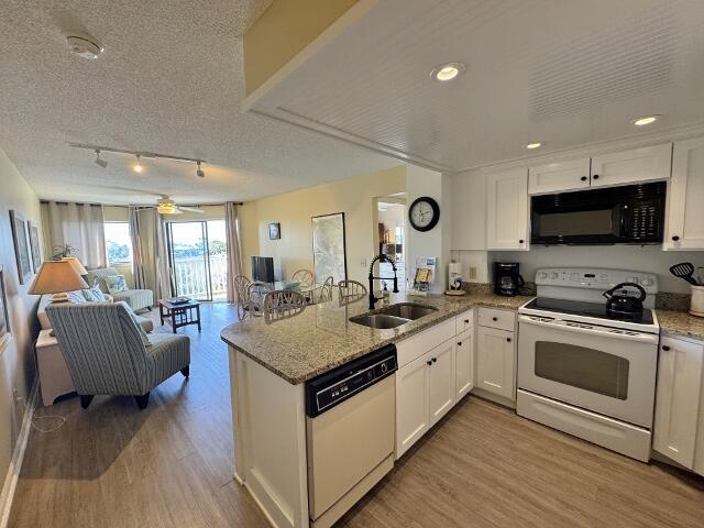 kitchen with white cabinets, kitchen peninsula, white appliances, and sink