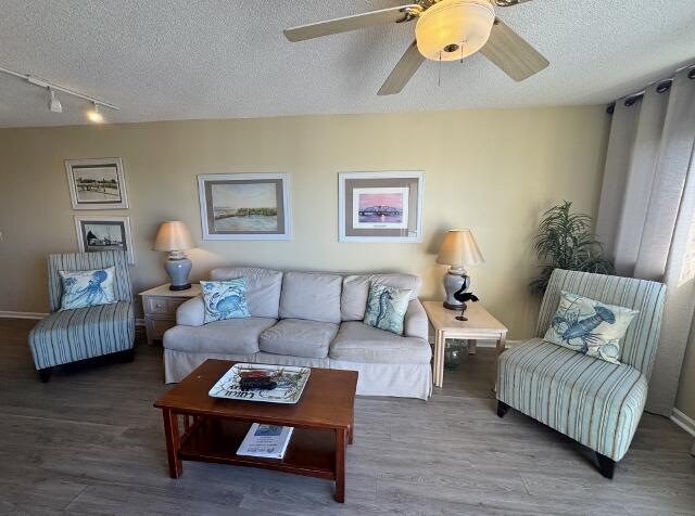 living room featuring ceiling fan, track lighting, wood-type flooring, and a textured ceiling