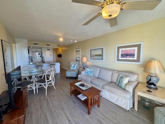 living room with hardwood / wood-style flooring, ceiling fan, a textured ceiling, and track lighting