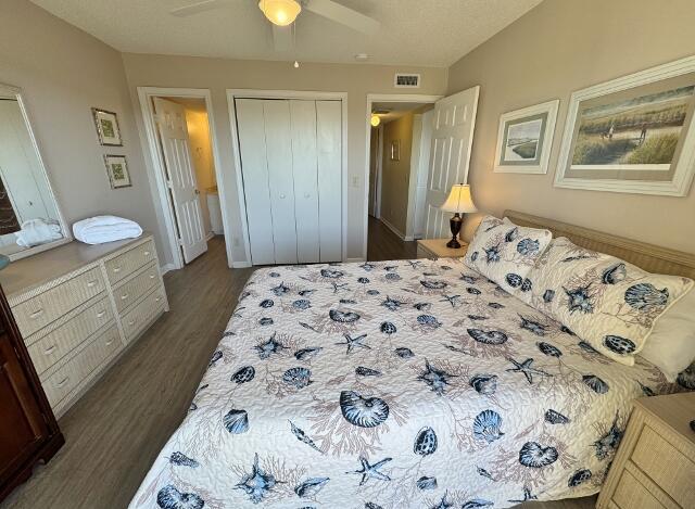 bedroom with dark hardwood / wood-style flooring, ceiling fan, and a closet