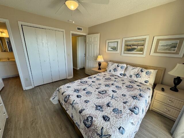 bedroom featuring ceiling fan, wood-type flooring, a textured ceiling, and a closet