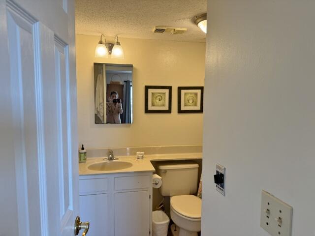 bathroom with vanity, toilet, and a textured ceiling