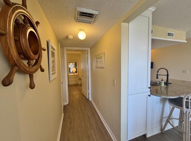 corridor featuring a textured ceiling, dark hardwood / wood-style floors, and sink