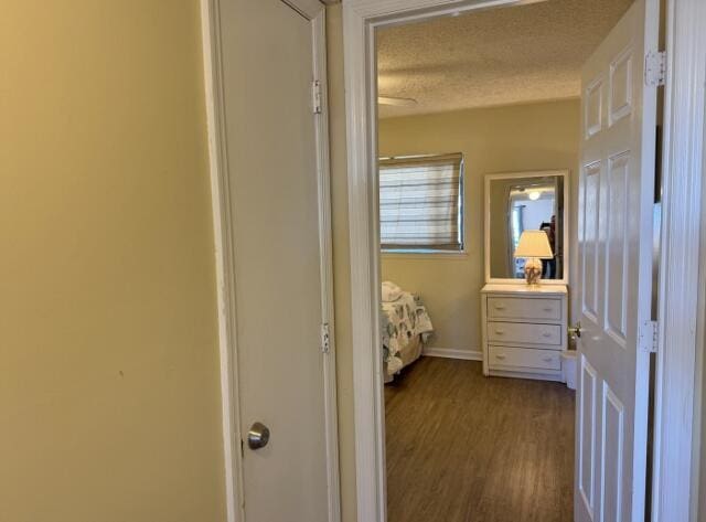 corridor with a textured ceiling and hardwood / wood-style flooring