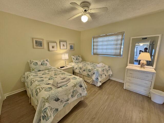 bedroom with ceiling fan, a textured ceiling, and light wood-type flooring