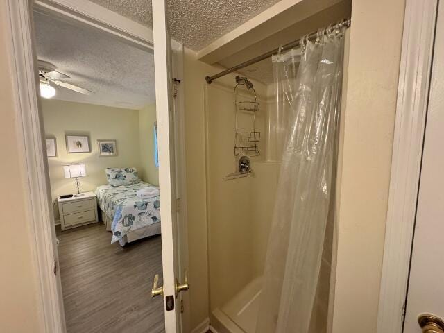 bathroom with a shower with curtain, a textured ceiling, hardwood / wood-style flooring, and ceiling fan