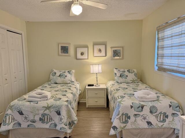 bedroom featuring a textured ceiling, light hardwood / wood-style flooring, a closet, and ceiling fan