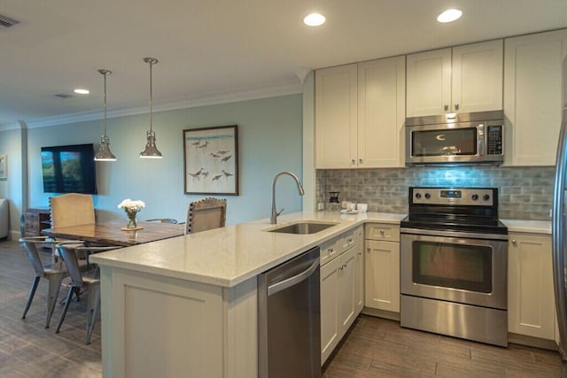 kitchen featuring appliances with stainless steel finishes, ornamental molding, a peninsula, a sink, and backsplash