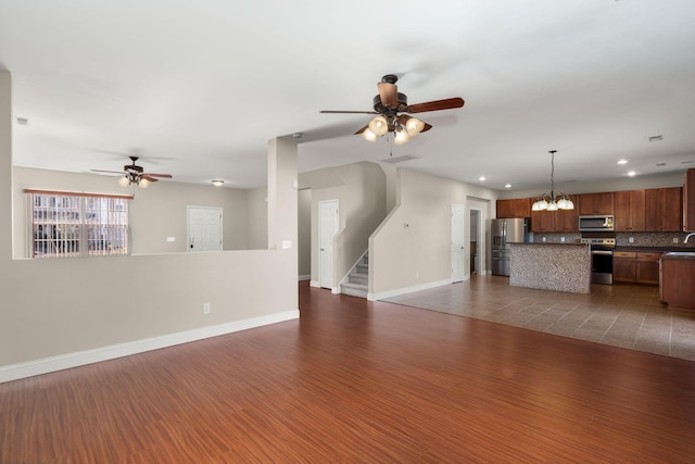 unfurnished living room featuring ceiling fan with notable chandelier and dark wood-type flooring