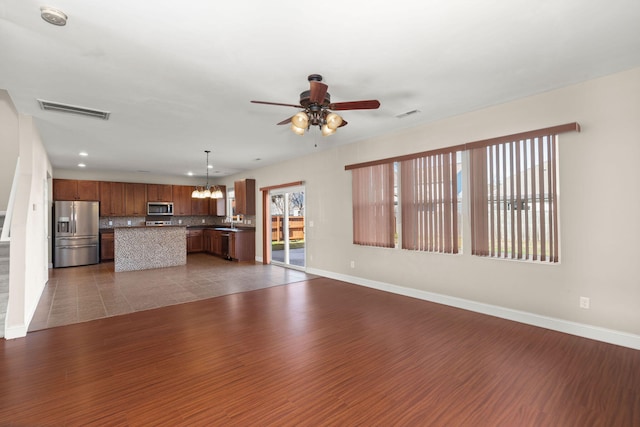 unfurnished living room with dark tile patterned floors and ceiling fan with notable chandelier