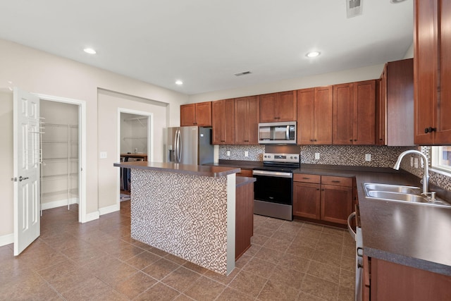 kitchen featuring appliances with stainless steel finishes, a center island, tasteful backsplash, and sink