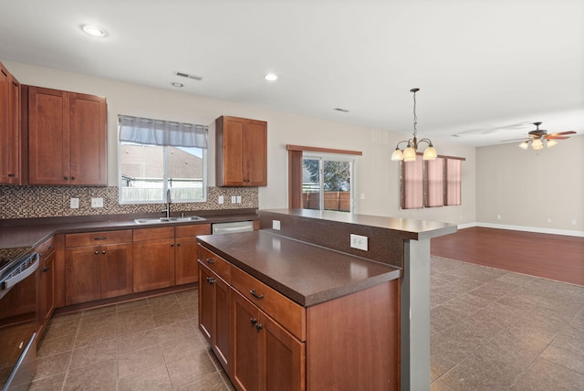 kitchen with decorative backsplash, appliances with stainless steel finishes, ceiling fan with notable chandelier, sink, and pendant lighting