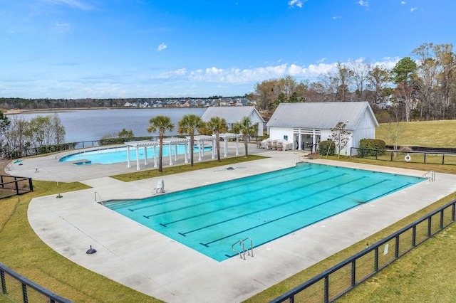 view of pool with a water view, an outdoor structure, a patio, and a yard