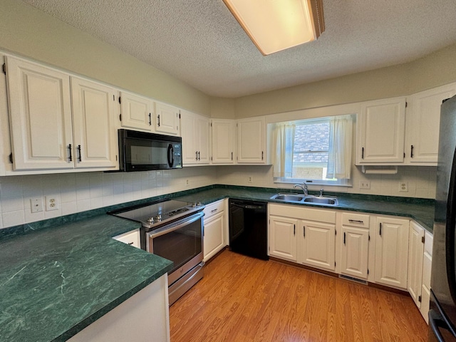 kitchen featuring black appliances, sink, backsplash, white cabinets, and light hardwood / wood-style flooring