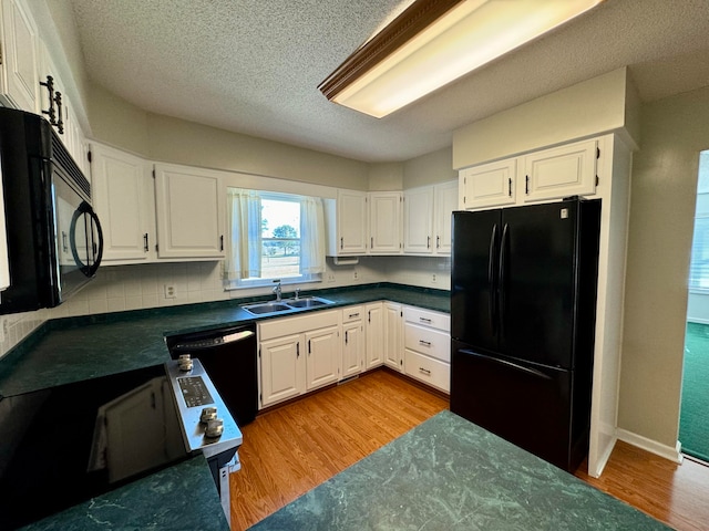 kitchen featuring sink, black appliances, white cabinetry, and light hardwood / wood-style flooring