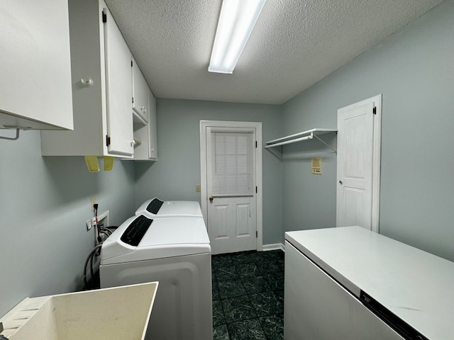 laundry area featuring sink, a textured ceiling, washing machine and clothes dryer, and cabinets