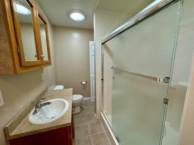 bathroom featuring vanity, toilet, tile patterned floors, and a shower with shower door