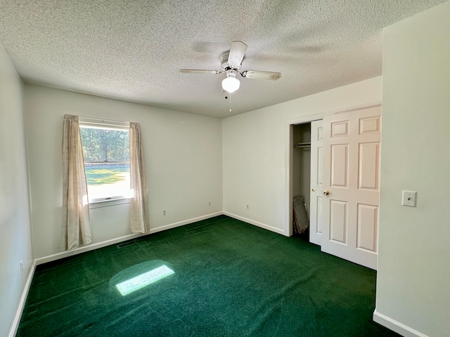 unfurnished bedroom featuring a closet, a textured ceiling, dark carpet, and ceiling fan