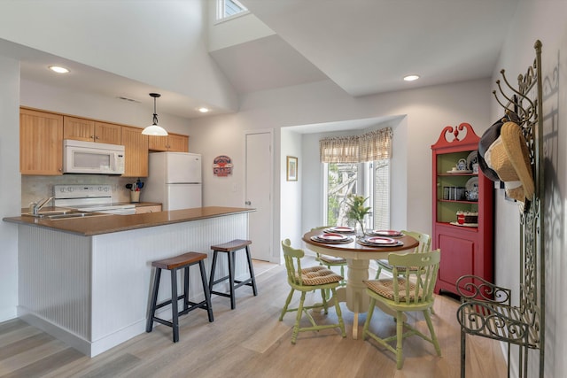 kitchen featuring light hardwood / wood-style floors, white appliances, decorative light fixtures, decorative backsplash, and kitchen peninsula