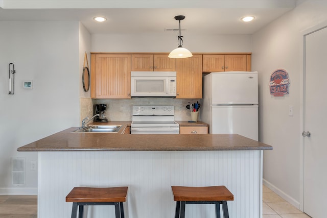 kitchen featuring white appliances, a breakfast bar area, sink, decorative backsplash, and hanging light fixtures