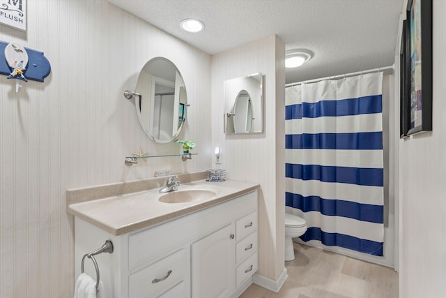 bathroom with a shower with curtain, vanity, toilet, and a textured ceiling