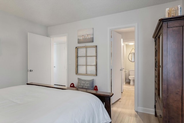 bedroom featuring ensuite bathroom, light wood-type flooring, and a textured ceiling